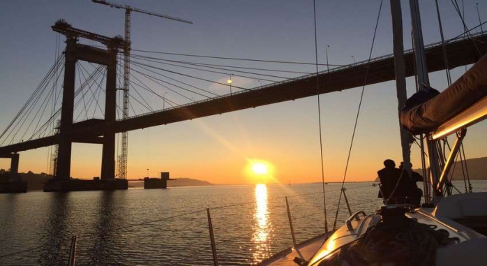 Puesta de sol en desde la Ría de Vigo tomada desde un barco de Sailway Turismo Náutico con la silueta del Puente de Rande de fondo. Siente Galicia.