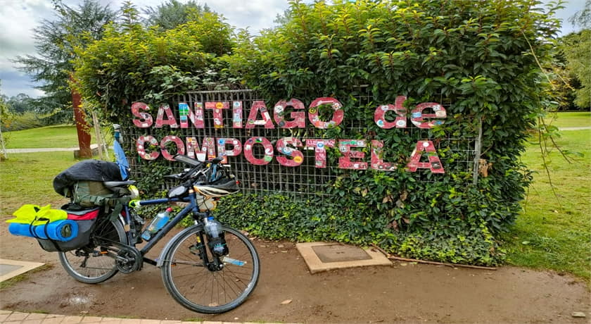Bicicleta de peregrino delante de un cartel que pone Santiago de Compostela